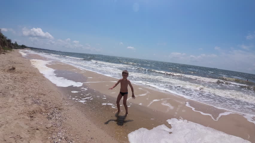 Happy Boy Running and Dancing on a Sea Shore Before Swimming in Shallow Waves on a Beach