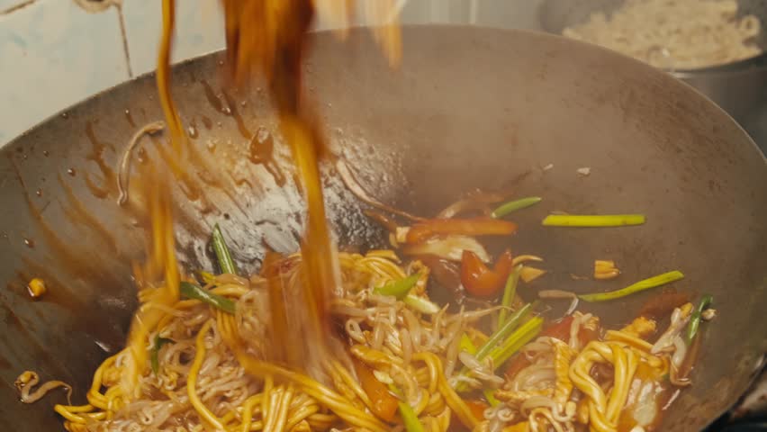 Asian Wok noodles cooking, Chef cooking handmade pasta wok frying pan close-up. Chinese traditional beef and chicken vegetables on fire pan, japanese korean pasta. Restaurant Food concept. Sea food.