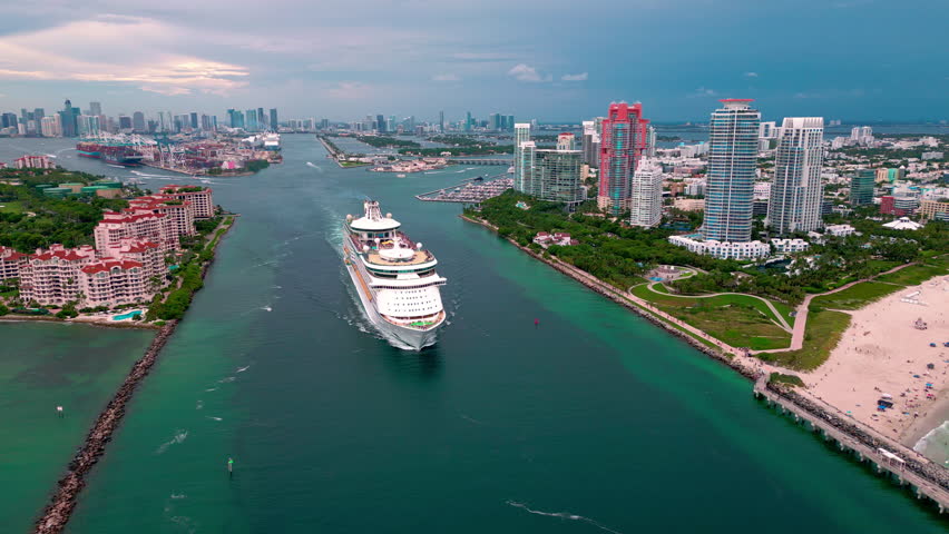 Cruise ship along Miami beach coast. Cruise summer luxury vacation in Miami. Cruise travel near Miami city skyline. Cruise liner journey. Summer tropical tourism.