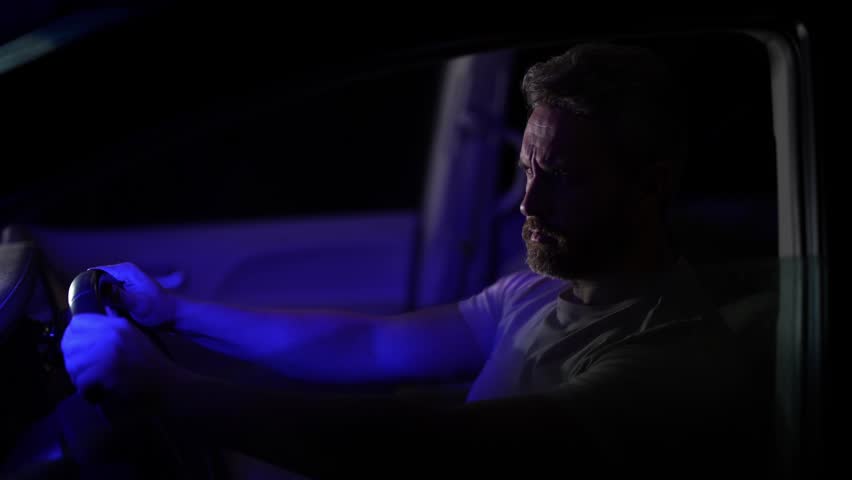 Driver man in crime driving car at night. Alert driver man in car during police siren. Crime scene with drivers inside car at night. Police siren chasing driver in night. Man driver feels alert.