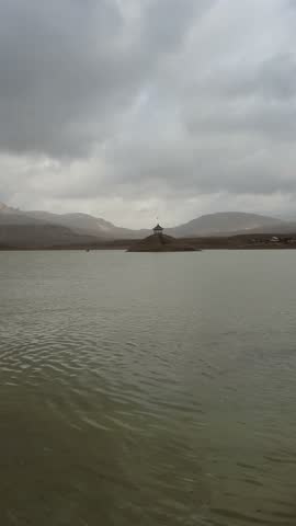 Lake with temple on island, serene landscape, cloudy sky, tranquil atmosphere, scenic view