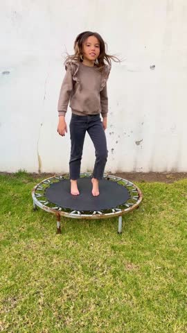 Little Girl Having Fun Playing on Mini Trampoline in Home Garden
