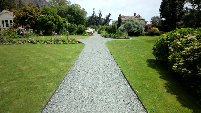 Walking along gravel path through lush garden near house