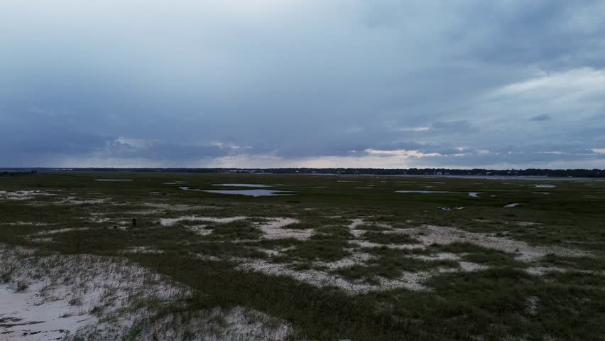 An aerial view of the dunes and wetlands with a storm rolling in.