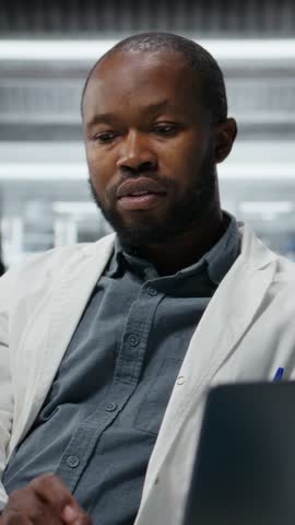 Vertical video Lab researcher using laptop software to evaluate compound solutions for new drug formulation. Chemist in laboratory testing experimental medication in vial, inputting data on notebook