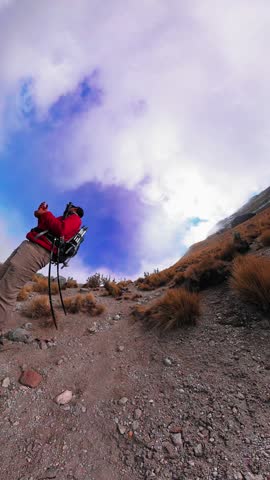 Low angle view of a man hiking a steep volcanic trail in mexico under a dramatic cloudy sky