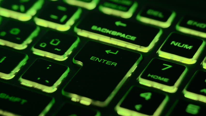 Green backlit keyboard with dynamic light streaks created by fast zoom motion and long exposure, focusing on the Enter key. Futuristic technology background.