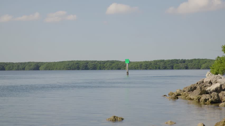 Shot of a navigational sign with shore rocks in foreground in the ocean at Biscayne National Park, Florida. Calm waters and clear skies make this ideal for marine, boating, or nautical projects.