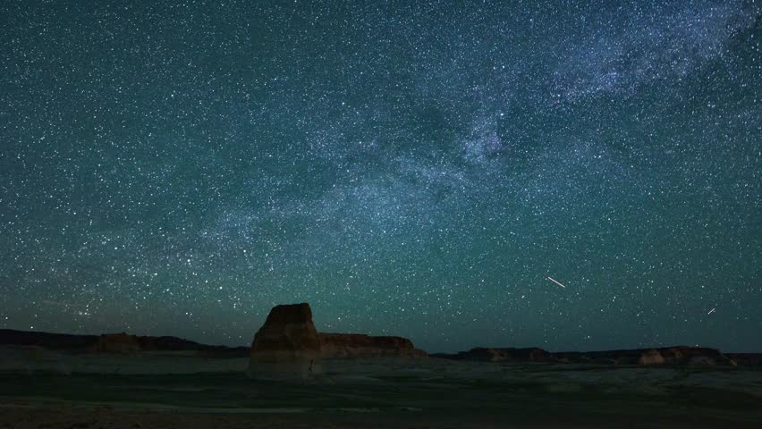 Night sky timelapse shows milky way over desert butte landscape