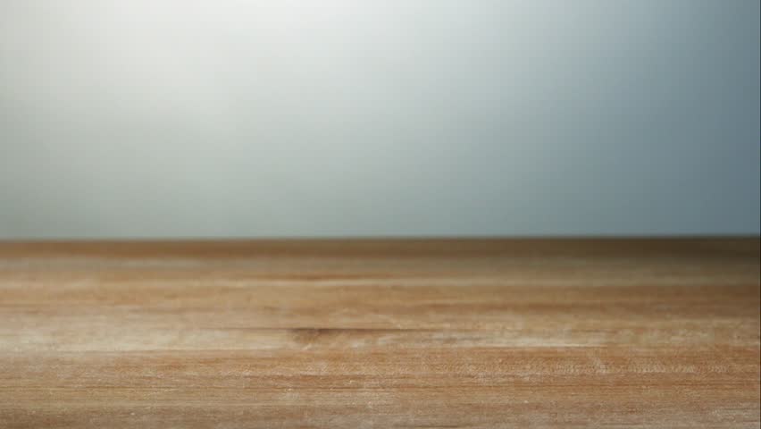Multiple Red Garlic Cloves Falling And Bouncing On A Light Brown Wooden Table Surface