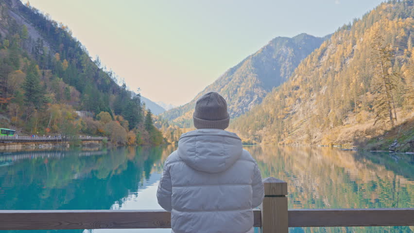 Happy woman traveler travel in jiuzhaigou national park in Sichuan, China. Tourist sightseeing Panda lake and snow mountain in Autumn season. Famous Landmark and Vacation near Chengdu, China