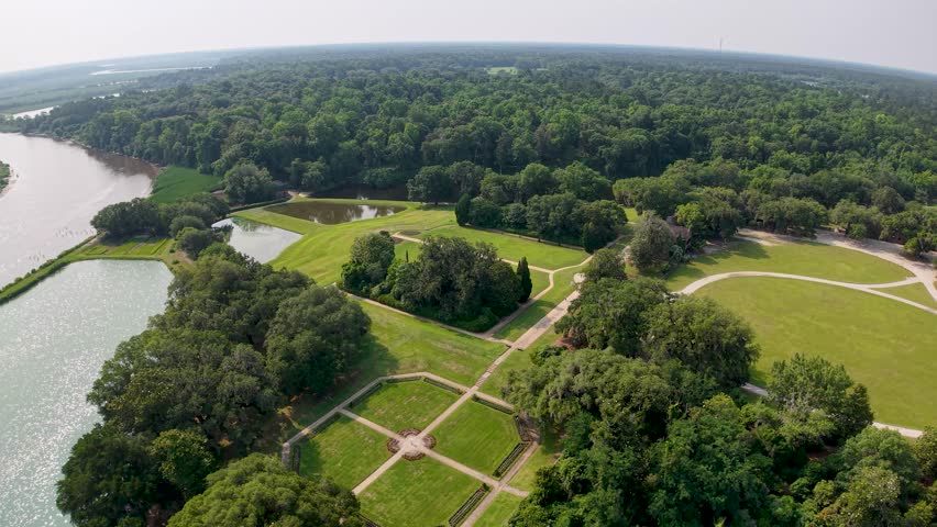 Aerial drone footage shows Middleton Place Plantation near Charleston South Carolina with a river beside manicured lawns garden paths and treed fields.
