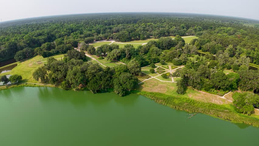 Drone footage of Middleton Place Plantation captures a calm lake or lagoon bordered by forested banks and manicured clearings near Charleston South Carolina.
