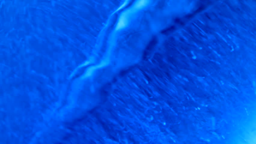 Extreme close up of blue chemicals being mixed in lab beaker, shot in HD video