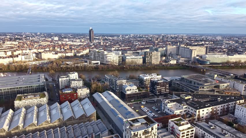 Panning drone fly of Nantes cityscape near Loire River with Haudeline bridge, Nantes University Hospital and Tour Bretagne tower in background, Nantes, Loire-Atlantique, France