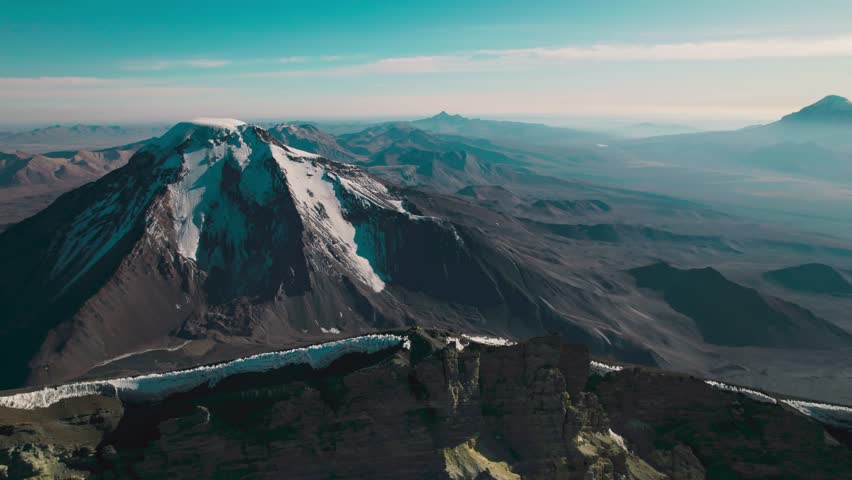 Parinacota Volcano summit. The contrast between snow-capped volcanic peaks and the rugged, arid terrain of the Bolivian Altiplano.