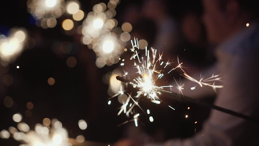 People holding sparklers at night, celebrating with lights and joy, capturing festive moments, happiness, and magical evening atmosphere.