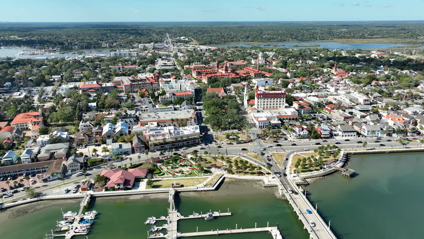 A sweeping drone perspective captures downtown St. Augustine’s historic core, waterfront harbor, and iconic bridge.