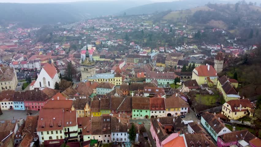 Old town of Sighisoara, Romania, with the Clock Tower rising above historic rooftops and hillside architecture.