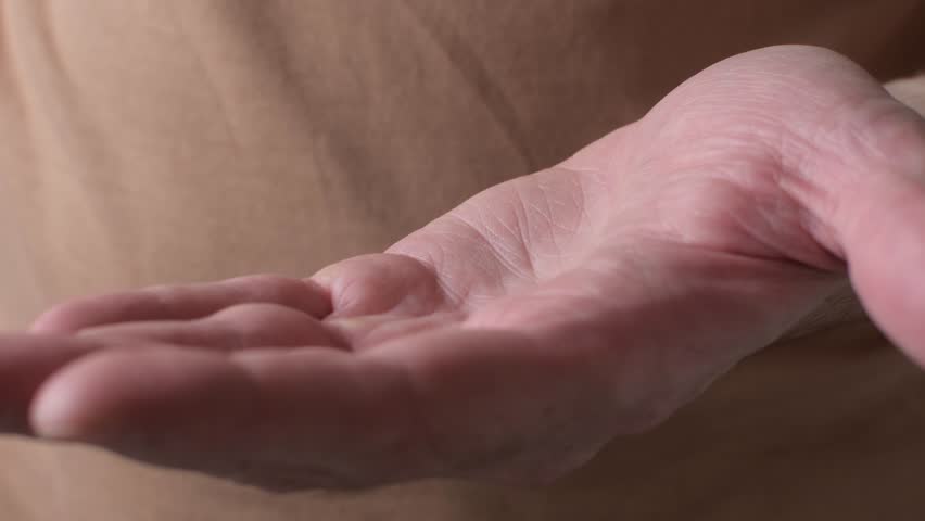 Man pours excessive supplement capsules from amber bottle into open palm, concept of overdose, unsafe daily dosage and misuse