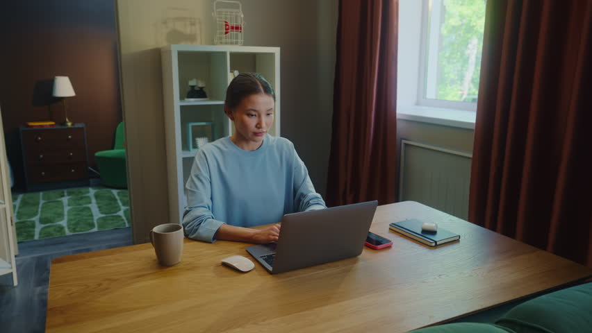 Asian woman worker remote hard work laptop home. Girl talk mobile cell phone. Female employee answer call. Busy ceo person use pc. Online education. Computer freelance. Distant consult center job.