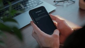 Close up of hands holding smartphone with AI chatbot app at workspace with laptop. Artificial intelligence assistant application helps improving business productivity.  - Powered by Shutterstock - Get 15% off with code: PIKWIZARD15