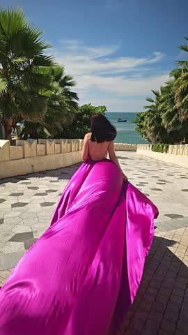 A woman in a bright pink dress poses against the backdrop of a European-style city, a girl in a dress with a long train, flying trail. A beautiful city in an old colonial style, Venice, the Venice of Vietnam
