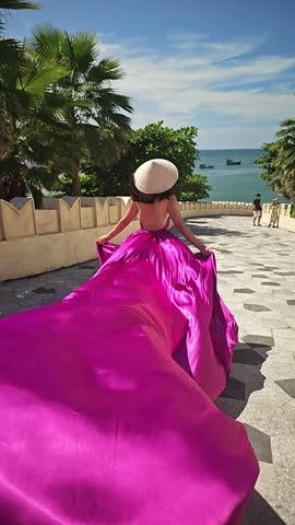 A woman in a bright pink dress poses against the backdrop of a European-style city, a girl in a dress with a long train, flying trail. A beautiful city in an old colonial style, Venice, the Venice of Vietnam