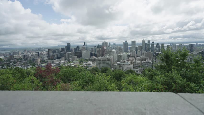 Handheld establishing of Montreal skyline from park overlook above city, Canada backdrop