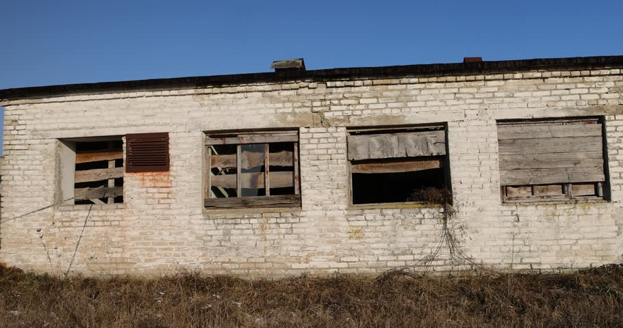 an old abandoned building made of brick in the winter, an building intended for demolition, the entrances and windows to the building are boarded up