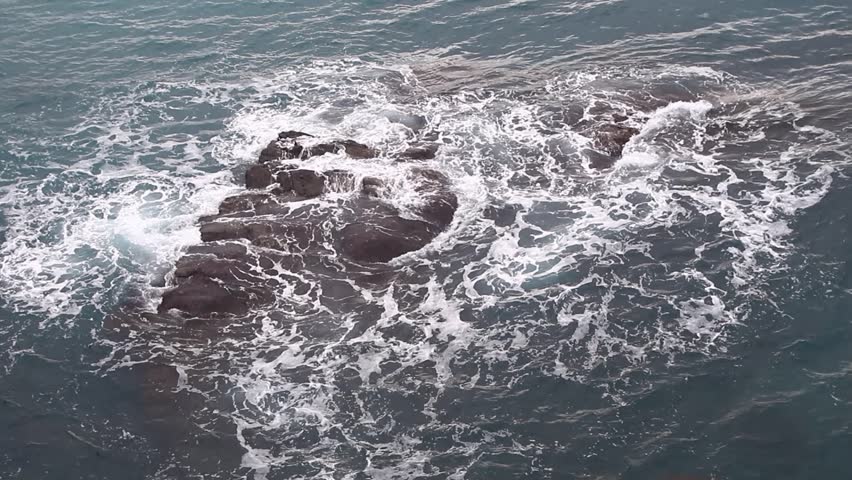 Gentle waves washing rocky shoreline Bogliasco Italy blue water