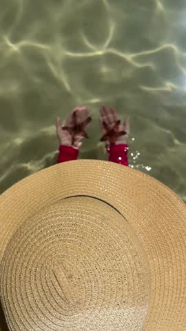 Young woman carefully examines big red starfish and gently releases it into the sea on the sand bottom, appreciating its beauty and the ocean