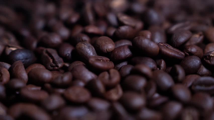 Close up of seeds of coffee. Fragrant coffee beans are roasted smoke comes from coffee beans, with cup coffee