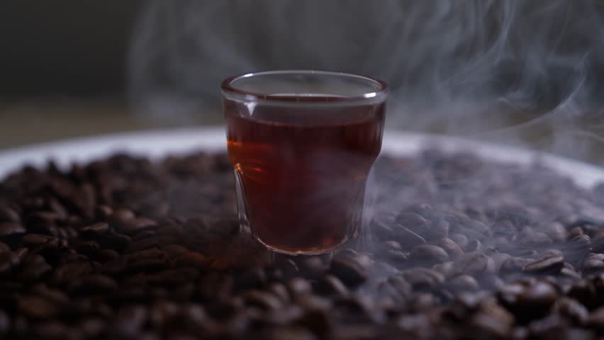 Close up of seeds of coffee. Fragrant coffee beans are roasted smoke comes from coffee beans, with cup coffee