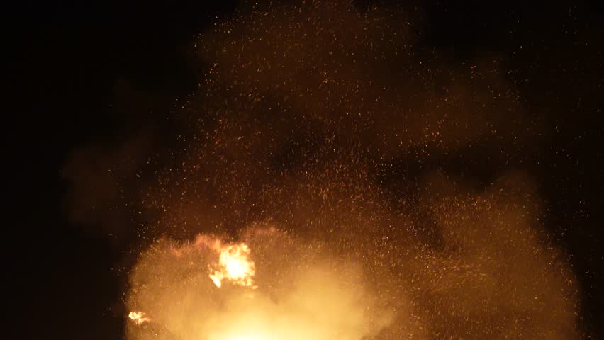 Burning fire with trails of embers floating up into the dark sky