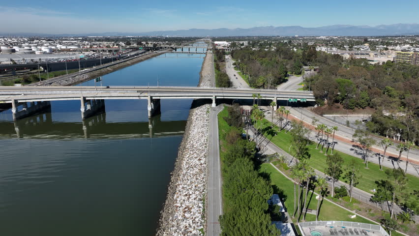 Long Beach, California, USA - High Drone View of Los Angeles River Bike Path Next to 710 Freeway With Bikers and Cars