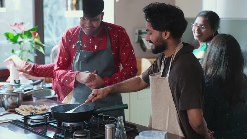 A man cooks in a frying pan and flips the pita bread with a spatula while a group of four friends are nearby