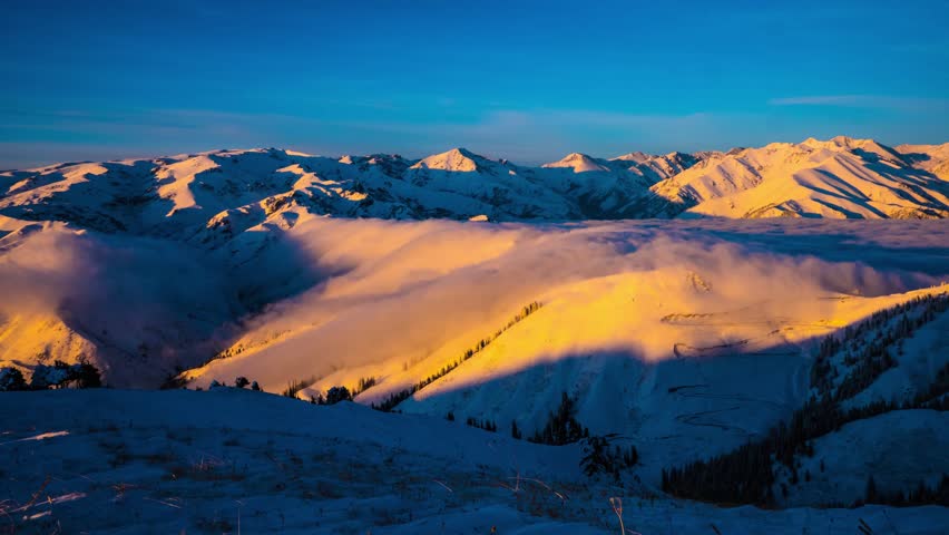 Breathtaking 4K UHD aerial time-lapse footage of snow-capped mountain ranges, sunlit Golden Peaks, and majestic plateau glaciers, showcasing the raw beauty of high-altitude alpine landscapes. Capturing golden hour light gilding snow peaks, drifting cloud seas over frozen glaciers, and rugged ice cliffs glistening in sunlight, the video embodies the grandeur of plateau wilderness. Perfect for Shutterstock users—ideal for travel promotions, adventure campaigns, nature documentaries, and commercial projects seeking visually striking alpine scenery.