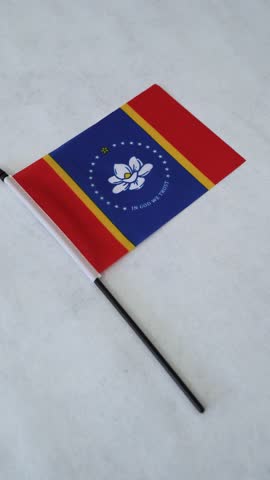 Vertical shot of Mississippi state flag. Camera orbiting.