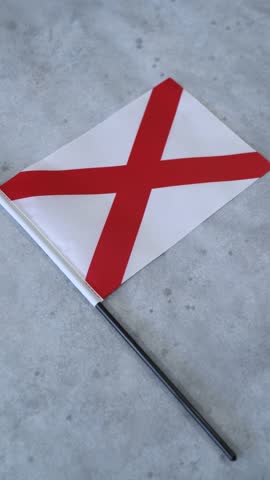 Alabama state flag. Vertical shot on grey background.