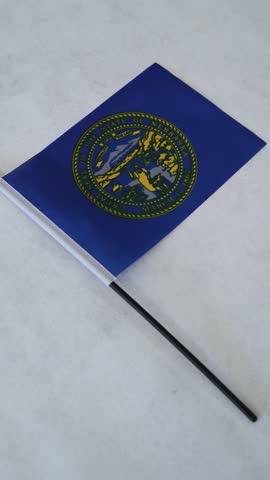 Vertical shot of Nebraska state flag on white background.