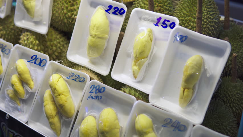 Durian fruit at a night food market in a Chinatown. Closeup view of yellow ripe edible flesh of durian. The king of fruits is a popular dessert in Asia.