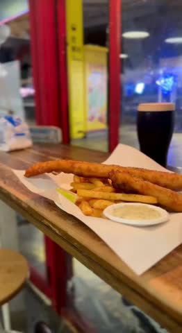 Golden fish and chips served with salmon pasta in a cozy British-style rustic restaurant.