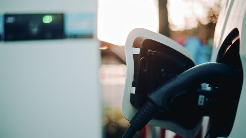 Charging station display and car front, with the EV plugged in and the headlight slightly blurred