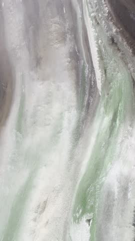 Close-up of hot spring water flowing down a colorful green mineral rock wall at Lisong Hot Spring