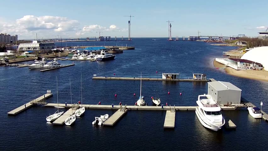 Breathtaking aerial views reveal a tranquil harbor filled with various boats. Clear blue skies enhance the serene coastal atmosphere, perfect for relaxation.