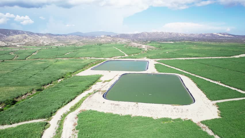 Drone aerial view of an irrigation reservoir used for drip farming in Barahona, showing water storage infrastructure surrounded by agricultural fields.