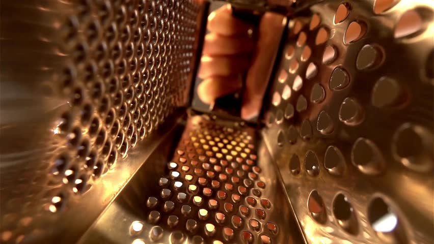 In a kitchen filled with warmth, someone grates cheese into a bowl, adding flavor to an upcoming meal. The cheese falls gracefully through the grater
