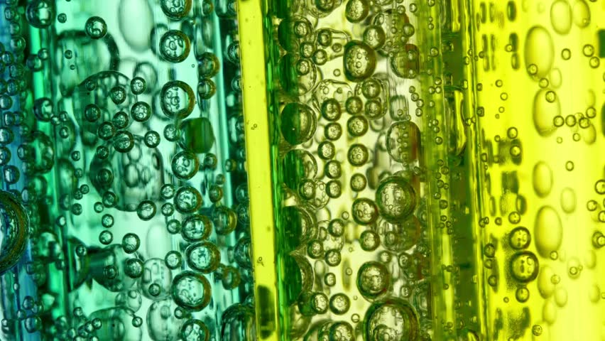 Macro close up shows rising bubbles within vertical bands of green and yellow liquid. Fizzy texture creates unique abstract pattern effect. Great for backgrounds. liquid with bubbles close up