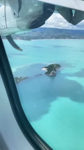 Aerial view of a tropical island and turquoise ocean from a propeller plane window